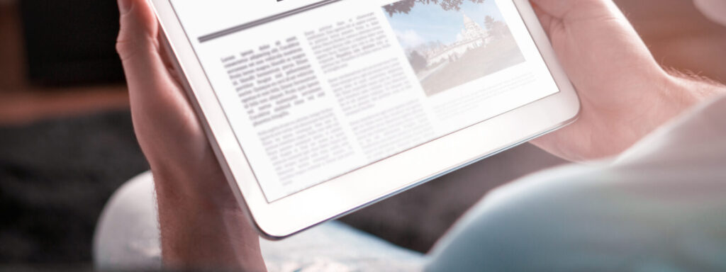 Man reading the news on tablet at home. Imaginary online and mobile news website, application or portal on modern touch screen display. Holding smart device in hand.